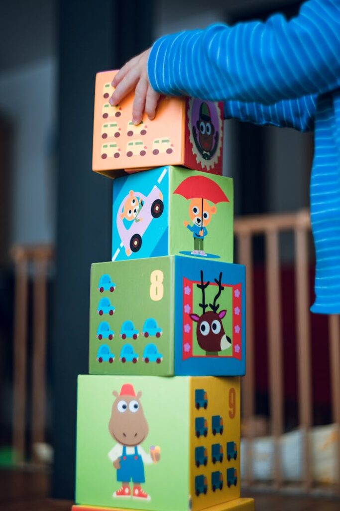 A child playing indoors, stacking colorful wooden toy blocks with joyful illustrations.